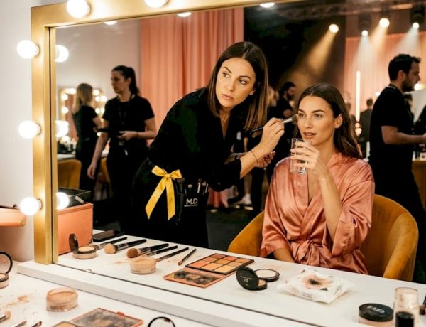 Make-up artist intenta a preparare le modelle dietro le quinte di una passerella